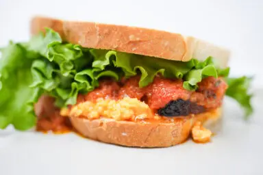 Crispy Pork Belly and Tomato Confit BLT: Succulent pork belly, tangy tomato confit, creamy pimento cheese, and crisp lettuce on toasted bread.