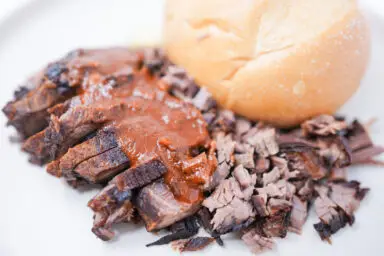 Juicy slices of sweet and tangy beef brisket drizzled with a rich, caramelized sauce, showcasing the perfect balance of smokiness and sweetness with a hint of tanginess
