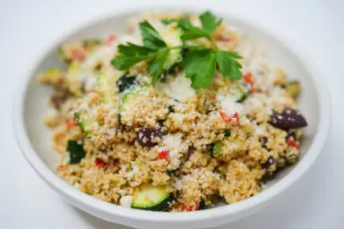 A colorful bowl of Grilled Zucchini Couscous Salad, featuring tender green zucchini slices, fluffy couscous grains, and bright vegetables, drizzled with a zesty lemon dressing.