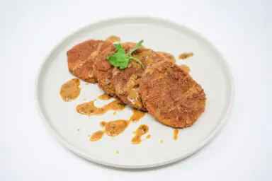 A plate of crispy Fried Green Tomatoes topped with a drizzle of rich, smoky Chipotle Honey Mustard Sauce, showcasing a golden crust and vibrant sauce for a contemporary twist on a Southern classic.